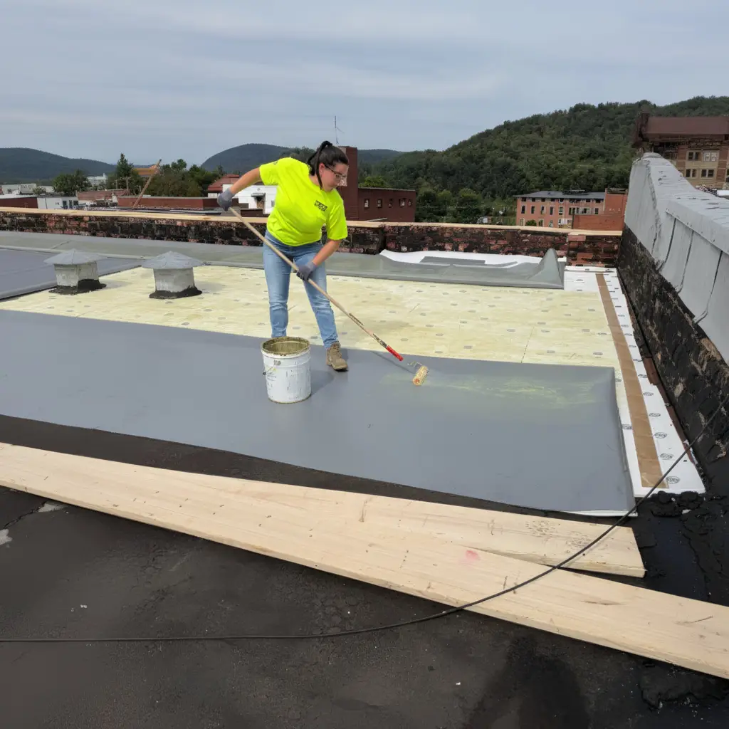 Home | Commercial Roofing Contractors PA RTG Solutions president Sarah Getz applies a roofing membrane during a commercial installation project, ensuring precise adhesion and long-term roof performance.