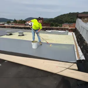 RTG Solutions president Sarah Getz applies a roofing membrane during a commercial installation project, ensuring precise adhesion and long-term roof performance.