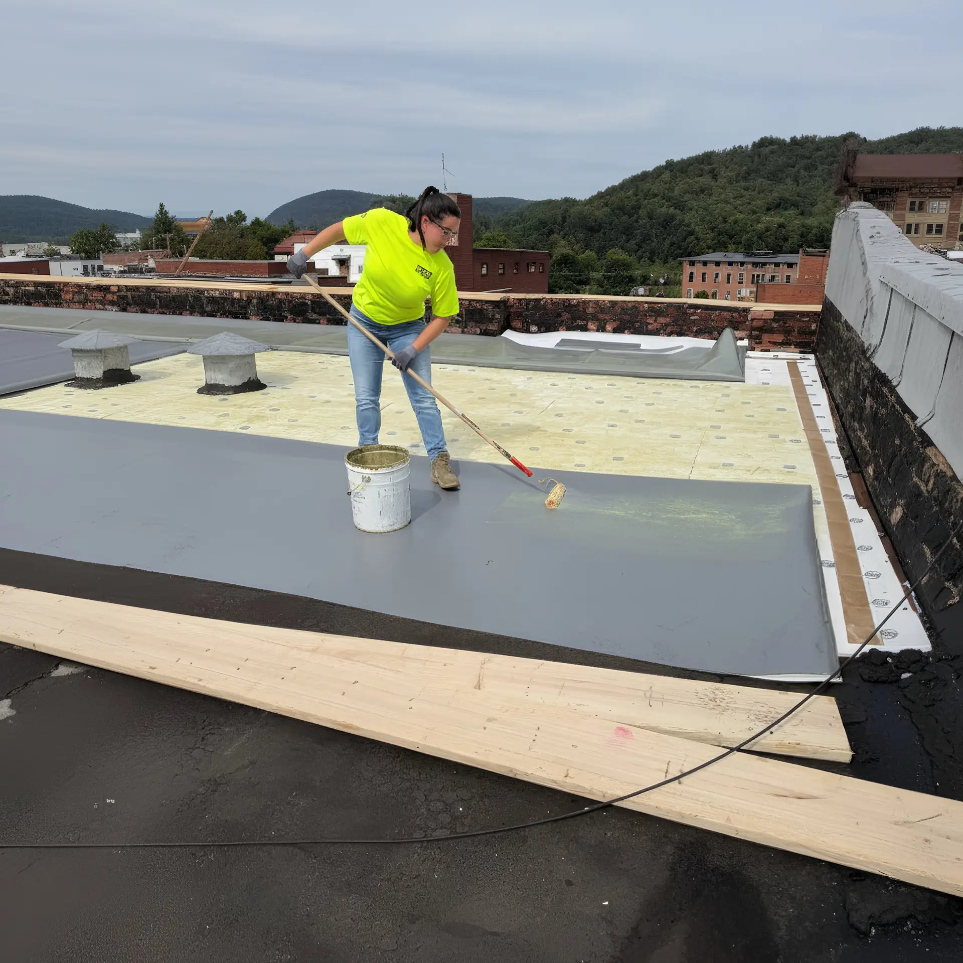 RTG Solutions president Sarah Getz applies a roofing membrane during a commercial installation project, ensuring precise adhesion and long-term roof performance.