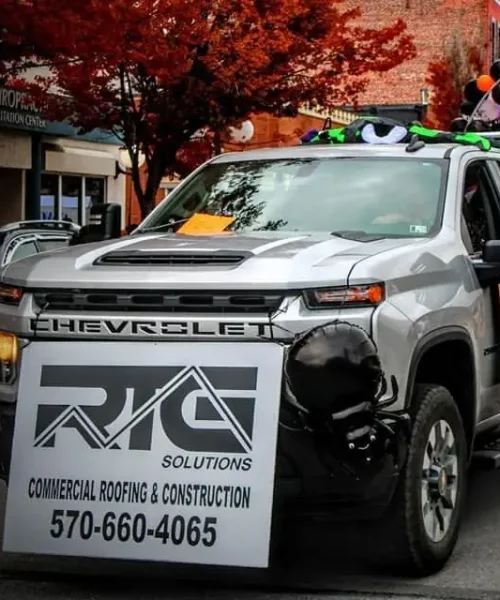 RTG Solutions team at the Lock Haven Halloween Parade with decorated float, balloons, and community members.
