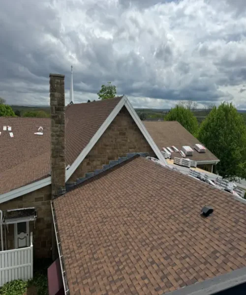 New asphalt shingles installed on pitched commercial church roof in Houtzdale, Pennsylvania, with roofing materials staged for completion.