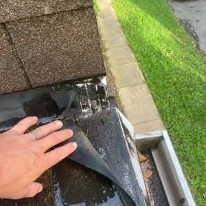 Commercial Roof Inspection Near Gutter Commercial roof inspection by a licensed RTG Solutions roofer showing lifted shingle and membrane near gutter.
