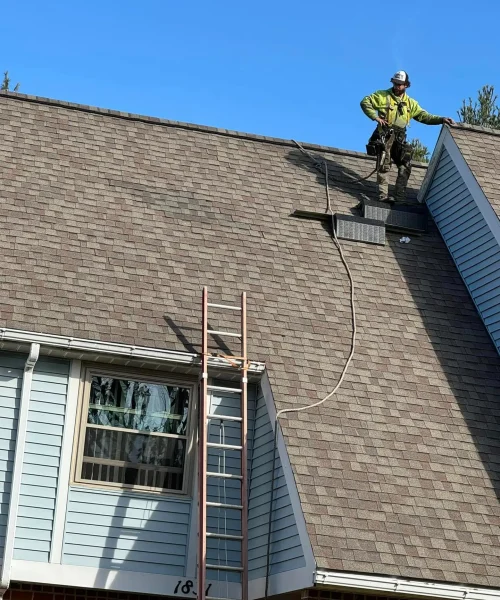Roofing contractor with safety harness conducting a roof inspections before repairing shingles on steep slope for Lycoming County Housing Authority