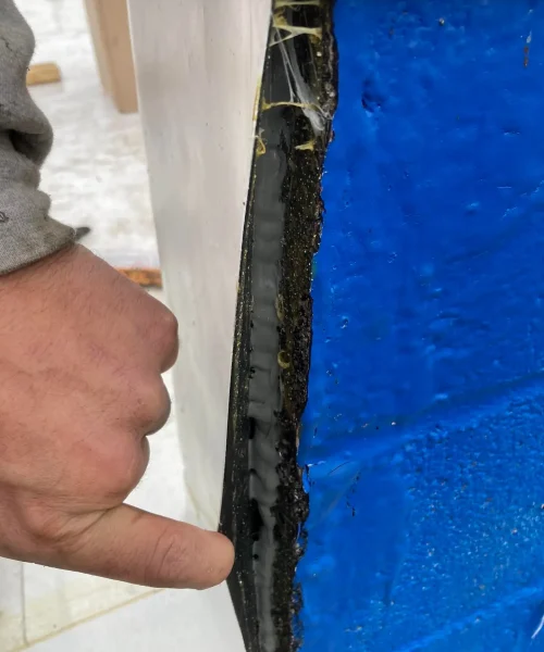 Roof inspection photo highlighting separation at wall seam allowing water intrusion